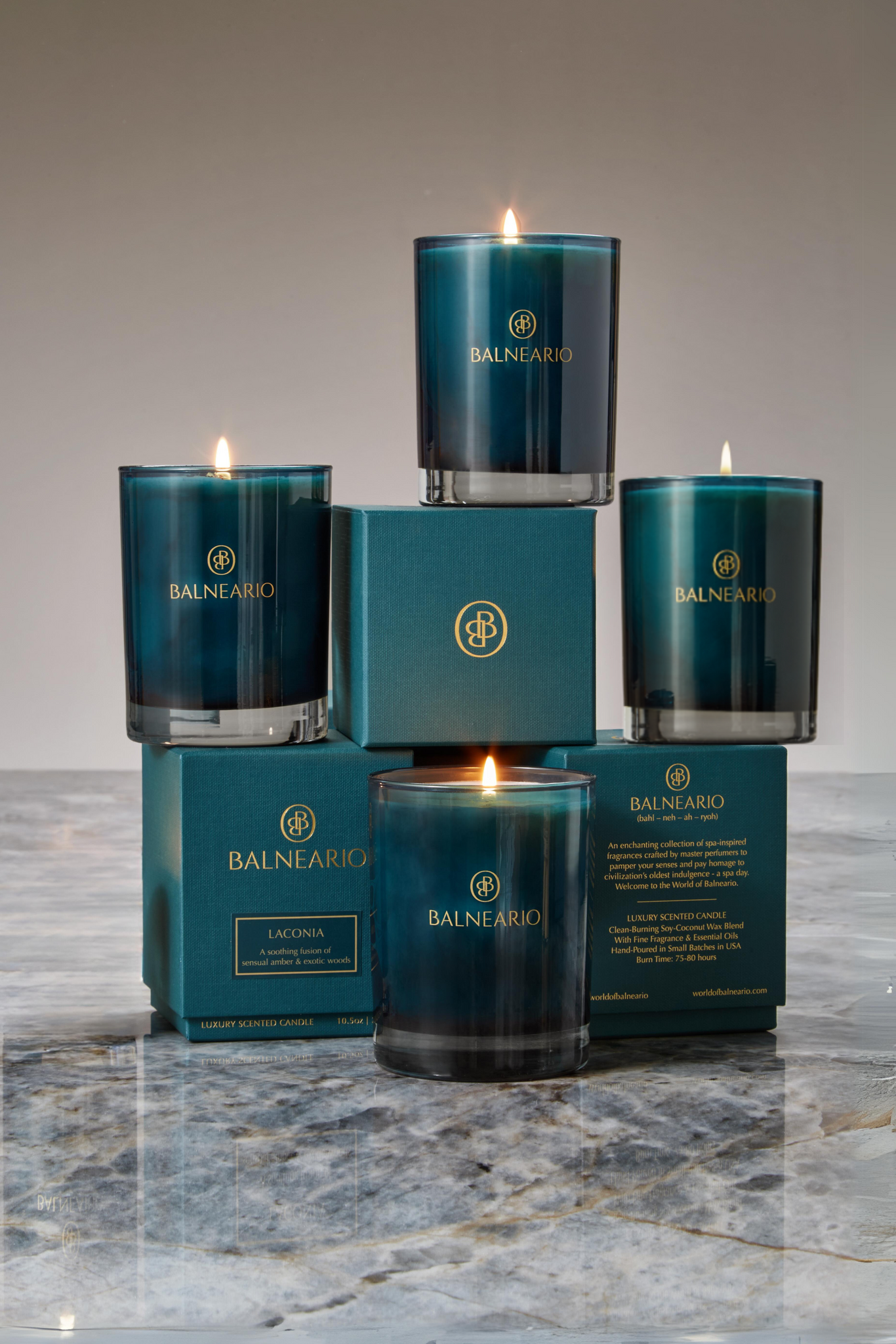 Four Balneario 10.5 oz Luxury Soy-Coconut Candles in teal glassware on signature teal boxes, artfully arranged