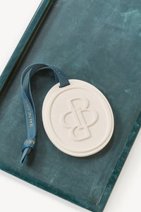 Balneario scented ceramic medallion with signature teal Balneario ribbon displayed on a teal tray