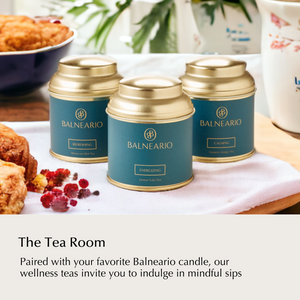 Balneario Wellness Tea Trio in teal tins with gold lids on a kitchen table surrounded by baked goods.