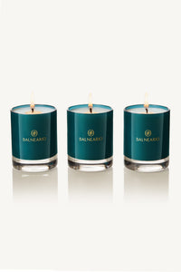 Three 2.5oz Balneario Luxury Soy-Coconut Votive Candles in teal glassware with flames.