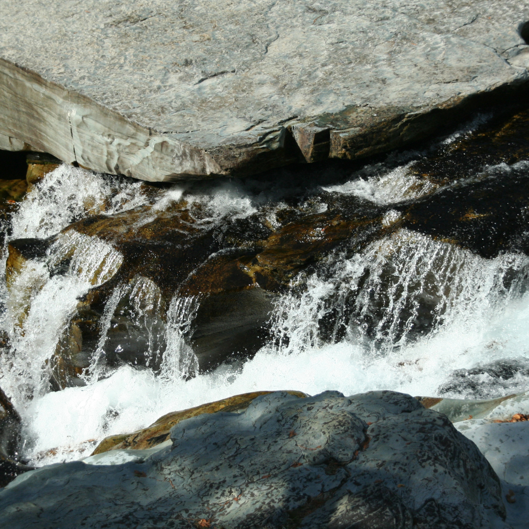 Closeup of mineral water over rocks, evoking the marine & floral fragrance notes prominent in the Balneario Coastal candle