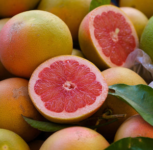 Close up of an open ruby red grapefruit, evoking the citrus and musk fragrance notes prominent in the Balneario Thermae candle